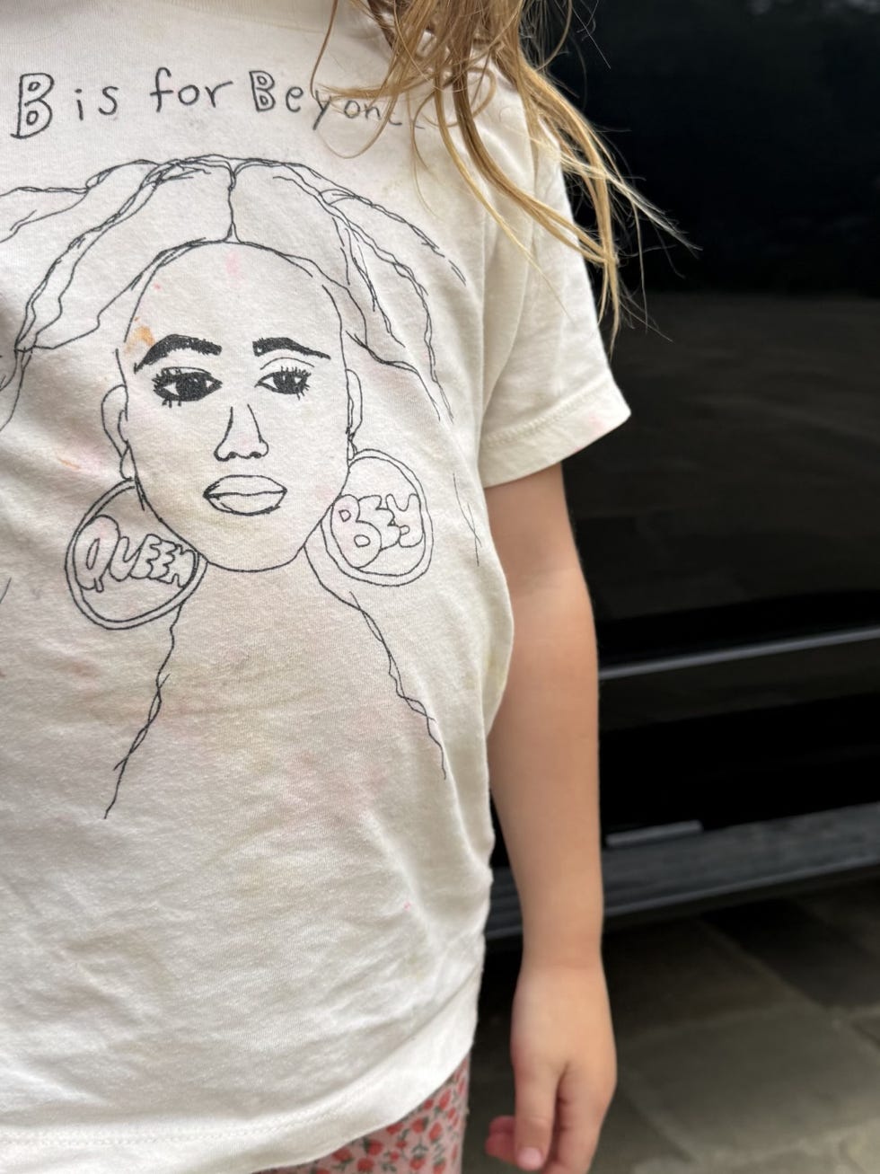 Dítě nosící tričko s kresbou obličeje a textem 'B is for Beyoncé'.
